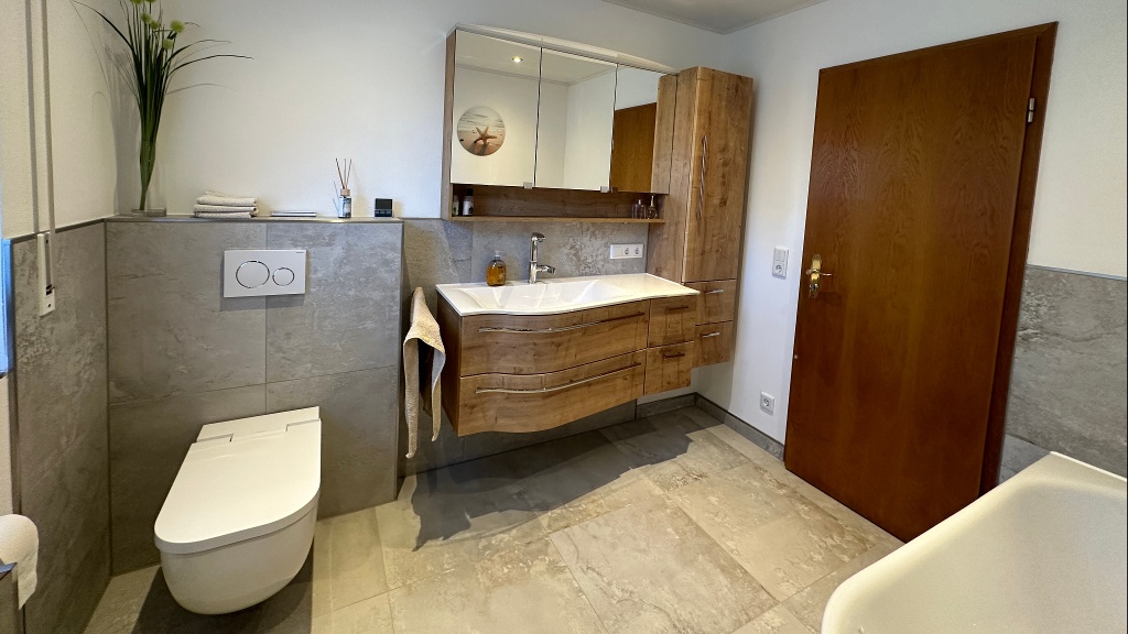 Das Badezimmer, sowie das nebenliegende Gäste-WC wurden in der Modernisierung zu einem Raum. Dadurch konnten sich die Kunden weiterhin den Wunsch von einer Badewanne, sowie einer großen begehbaren Dusche erfüllen.